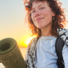 Woman holding a yoga mat with a sunset in the background