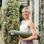 Jute Yoga Mat Sustainable Non-Slip Yoga Mat CompleteGrip™ Jute 4mm - Lady in London park holding a jute yoga mat  #colour_forest-green